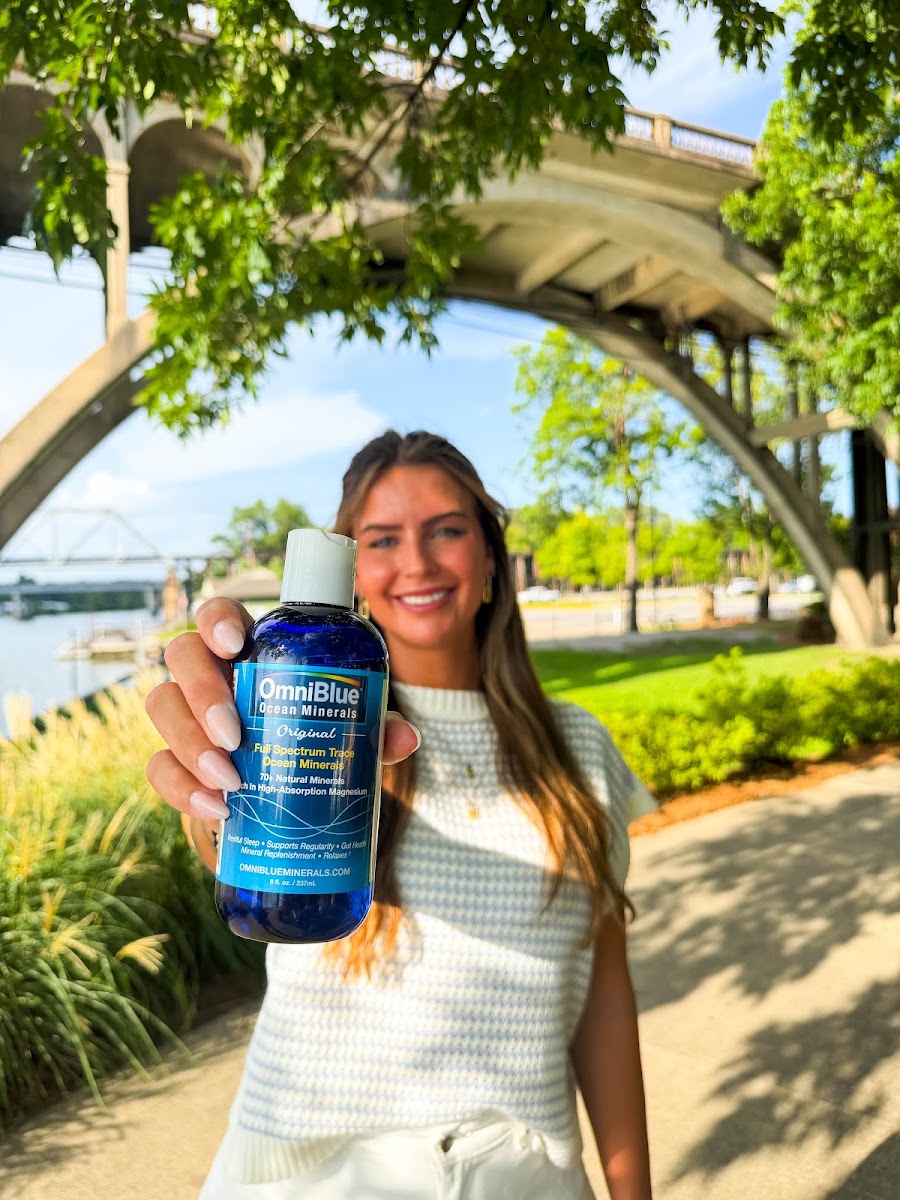 A woman holding a bottle of OmniBlue Original outdoors